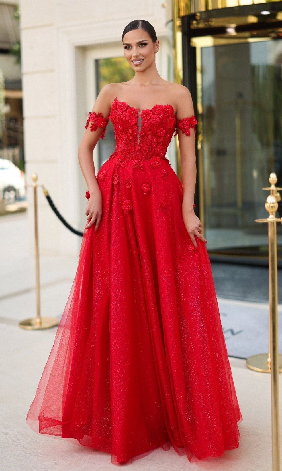 A woman in the Tina Holly TK582 long prom dress features a red corset bodice and shimmering glitter tulle—perfect for prom.